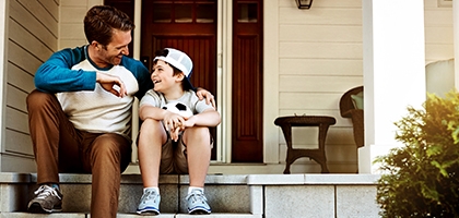 Father and his son laughing and talking on their porch at home.